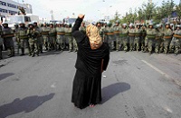  local woman on a crutch shouts at Chinese paramilitary police wearing riot gear 